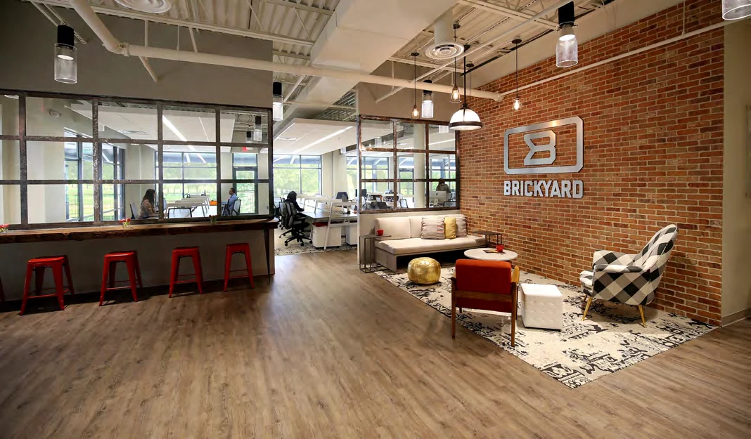 Casual coworking lounge with exposed brick, pendant lights, and warm natural materials at Brickyard