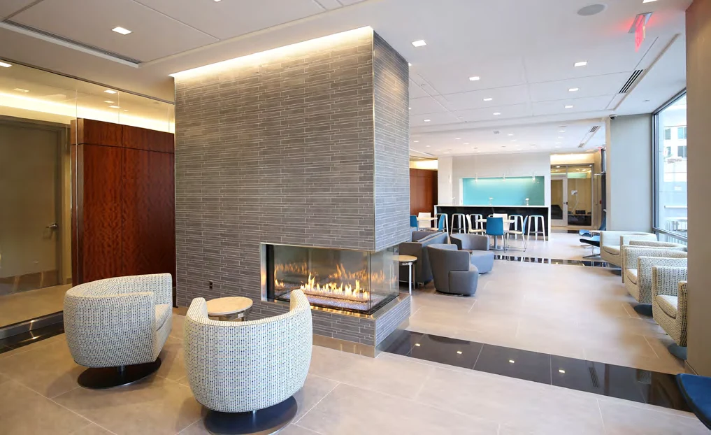 Resident lounge with a glass fireplace and curved wood wall at Randolph Towers