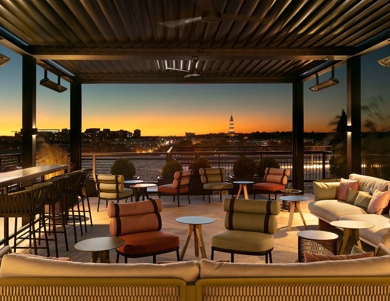 Warmly lit rooftop gathering space overlooking Alexandria at sunset